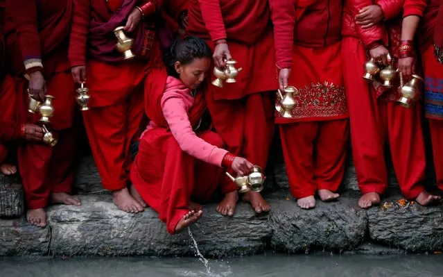 A Nepalese Hindu devotee washes her feet as she waits to collect holy water from Bagmati river to perform rituals during Madhav Narayan festival in Kathmandu, Nepal, Friday, January 24, 2020. During this month-long festival, devotees recite Holy Scriptures dedicated to Hindu goddess Swasthani and Hindu God Lord Shiva. Unmarried women pray to get a good husband while those married pray for the longevity of their husbands by observing month long fast. (Photo by Niranjan Shrestha/AP Photo)