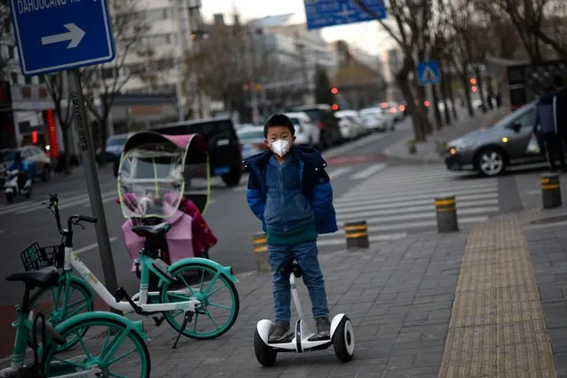 A child wearing a face mask rides a smart self-balancing scooter on a street, as the country is hit by an outbreak of the novel coronavirus, in Beijing, China on February 18, 2020. (Photo by Tingshu Wang/Reuters)