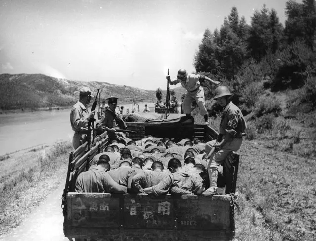 South Korean military policemen stand over a group of 'political prisoners' on their way to execution in the Taejon area during the Korean War.  Accused of treachery, they are forced to sit in a lorry with their heads bowed. 1950. (Photo by Haywood Magee)