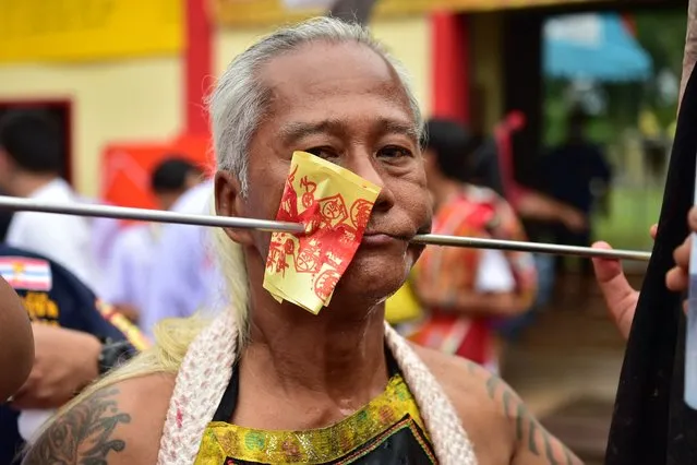 A man looks on after having his cheeks impaled as he takes part in an annual parade in honour of the the goddess of the Gow Lengchi Shrine, a traditional Chinese-style shrine in Narathiwat town, in Thailand's southern Narathiwat province on July 13, 2022. (Photo by Madaree Tohlala/AFP Photo)