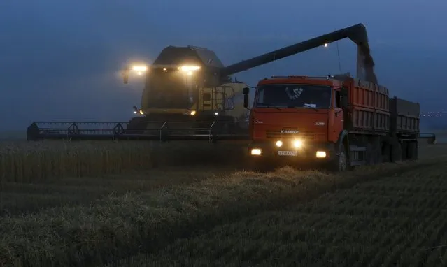 A combine harvester loads a truck with wheat after sunset on a field of the Solgonskoye farming company near the village of Talniki, southwest from Siberian city of Krasnoyarsk, Russia, August 27, 2015. (Photo by Ilya Naymushin/Reuters)