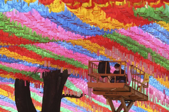 A worker wearing a face mask watches his smart phone under lanterns in preparation for the upcoming birthday of Buddha on April 30 at the Chogyesa temple in Seoul, South Korea, Sunday, March 8, 2020. The number of infections of the COVID-19 disease continues to spread around the globe. (Photo by Ahn Young-joon/AP Photo)