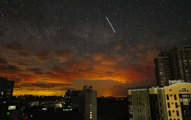 A photo taken using a slow shutter speed shows the orange glow of an ongoing battle projected on the clouds as a satellite (C, top) crosses the starry sky above the outskirts of Kharkiv, Ukraine, 19 May 2022 (issued 20 May 2022). Russian troops were recently pushed out from Kharkiv's outskirts by the Ukrainian army. The eastern Ukrainian city of Kharkiv and its surroundings witnessed repeated airstrikes from Russian forces. On 24 February, Russian troops invaded Ukrainian territory starting a conflict that has provoked destruction and a humanitarian crisis. (Photo by Pavlo Pakhomenko/EPA/EFE)