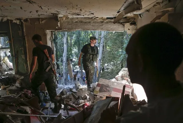 Armed pro-Russian separatists walk inside an apartment damaged by what locals say was recent shelling by Ukrainian forces in Donetsk August 23, 2014. (Photo by Maxim Shemetov/Reuters)