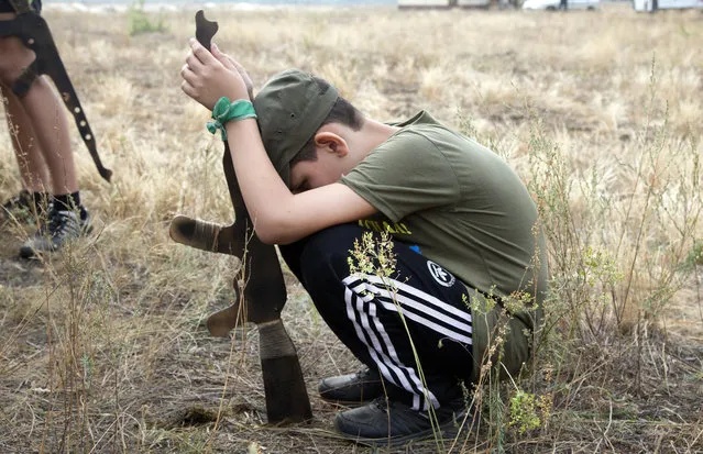 A boy has a rest at a military training ground of Ukraine's National Guard where professional servicemen are teaching children to operate weapons outside the village of Stare, the Kiev region, Ukraine, Saturday, August 29, 2015. (Photo by Efrem Lukatsky/AP Photo)