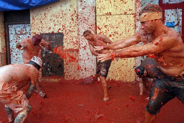 Men throw tomatoes at each other, during the annual “Tomatina” tomato fight fiesta in the village of Bunol, 50 kilometers outside Valencia, Spain, Wednesday, August 27, 2014. (Photo by Alberto Saiz/AP Photo)