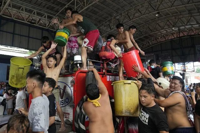 Residents refill plastic containers of water from a fire truck during a fire in Manila, Philippines, Tuesday, August 2, 2022. Fire authorities are still trying to investigate the cause of fire. No one was reportedly hurt during the incident. (Photo by Aaron Favila/AP Photo)