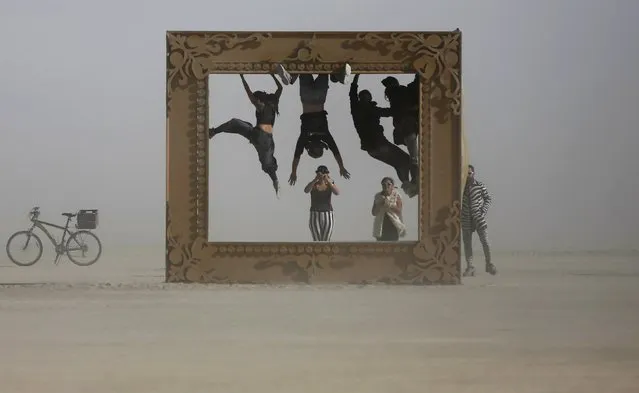 Participants climb the art installation “Got Framed” during the Burning Man 2015 “Carnival of Mirrors” arts and music festival in the Black Rock Desert of Nevada, September 4, 2015. (Photo by Jim Urquhart/Reuters)