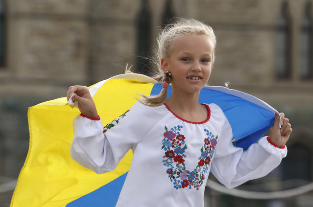 Orysia, 8, of Ottawa, runs with the Ukraine flag as people take part in Ukrainian Independence Day celebrations on Parliament Hill in Ottawa , Ontario, on Wednesday, August 24, 2022. (Photo by Patrick Doyle/The Canadian Press via AP Photo)