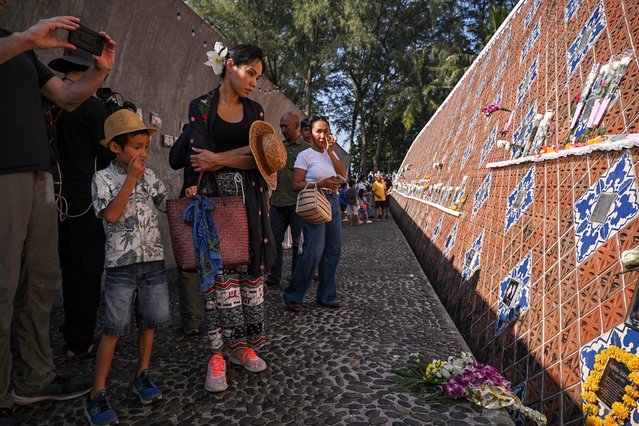 People look at portraits of tsunami victims at the Ban Nam Khem Tsunami Memorial wall in the southern Thai province of Phang Nga on December 26, 2024. Emotional ceremonies began across Asia on December 26 to remember the 220,000 people who died two decades ago when a tsunami devastated coastal areas around the Indian Ocean, in one of the worst natural disasters in human history. (Photo by Lillian Suwanrumpha/AFP Photo)
