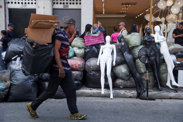 Shopkeepers take merchandise from stores near a shopping mall on fire in Sao Paulo, Brazil on October 30, 2024. (Photo by Carla Carniel/Reuters)