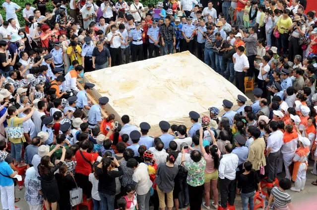 People take pictures of a piece of tofu, with a weight of eight tons, during an event in Huainan, Anhui province, September 15, 2015. (Photo by Reuters/China Daily)
