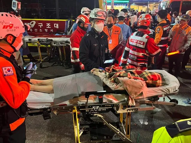 Rescuers move an injured person on a stretcher in Seoul's Itaewon district after a stampede during Halloween parties in Seoul, South Korea, 29 October 2022. At least 50 people suffer from cardiac arrest during a stampede in the Itaewon area of Seoul as a huge crowd came to celebrate Halloween, according to Yonhap news agency. (Photo by Jeon Heon-Kyun/EPA/EFE/Rex Features/Shutterstock)