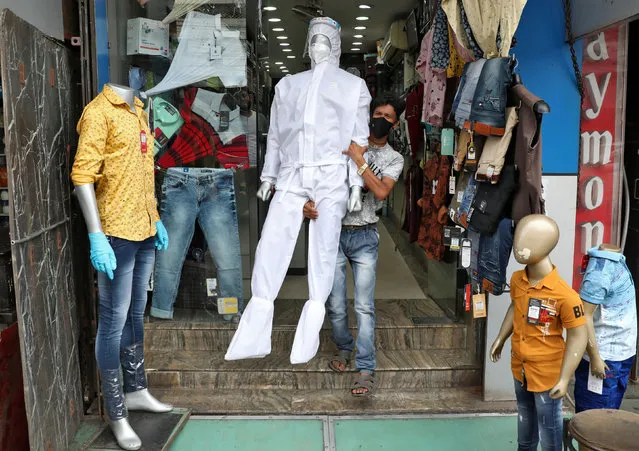 A worker carries a mannequin wearing protective gear for display outside a garment shop after shops reopened as India eases lockdown restrictions that were imposed to slow the spread of the coronavirus disease (COVID-19), in Kolkata, India, June 10, 2020. (Photo by Rupak De Chowdhuri/Reuters)