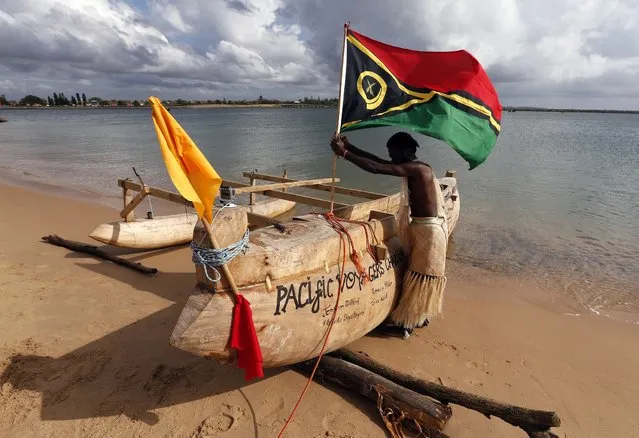 A traditionally dressed representative from a South Pacific nation installs a flag in a canoe on the shores of a beach as they prepare to participate in a protest aimed at ships leaving the Newcastle coal port, located north of Sydney October 17, 2014. (Photo by David Gray/Reuters)
