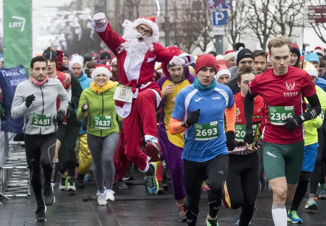A runner dressed like Santa Claus, runs from the start line of the traditional Christmas run along the streets of Vilnius, Lithuania, Sunday, December 17, 2017. The festive run attracts many hundreds of people to the capital dressed as Santa Clause to take part in the sporting event. (Photo by Mindaugas Kulbis/AP Photo)
