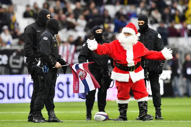 A man dressed as Santa gestures among members of police special officers during the French Top 14 rugby union match between Bordeaux-Begles (UBB) and La Rochelle (SR) on December 23, 2017 at the Matmut-Atlantique stadium in Bordeaux, southwestern France. (Photo by Nicolas Tucat/AFP Photo)
