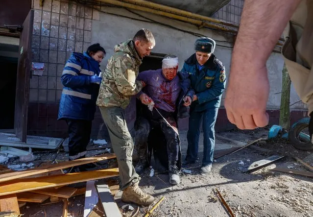 People help an injured man after a rocket hit a residential building in Donetsk, Ukraine, 06 December 2022. At least five people were injured when rockets hit a residential buildings and a food market during the morning of 06 December. (Photo by Sergei Ilnitsky/EPA/EFE/Rex Features/Shutterstock)