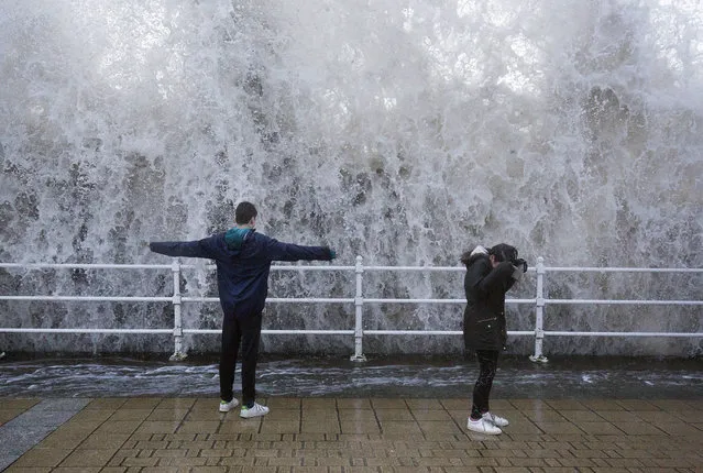 Children stand on the seafront as a wave crashes over the sea wall in Aberystwyth in west Wales as Storm Eleanor lashed Britain with violent storm-force winds of up to 100mph, leaving thousands of homes without power and hitting transport links Wednesday January 3, 2018. (Photo by Aaron Chown/PA Wire via AP Photo)
