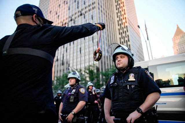 A demonstrator tries to provoke a law enforcement officer with a toy simulating a donut as they detain demonstrators during a protest against federal immigration sweeps next to the U.S. immigration court at the Jacob K. Javits Federal Building in New York City, U.S., June 11, 2025. (Photo by Eduardo Munoz/Reuters)
