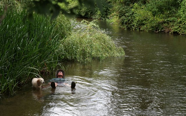 David Baddeley and his miniature Labradoodle, named Crumble, cool off in the River Colne in Rickmansworth, Britain on July 1, 2025. (Photo by Suzanne Plunkett/Reuters)