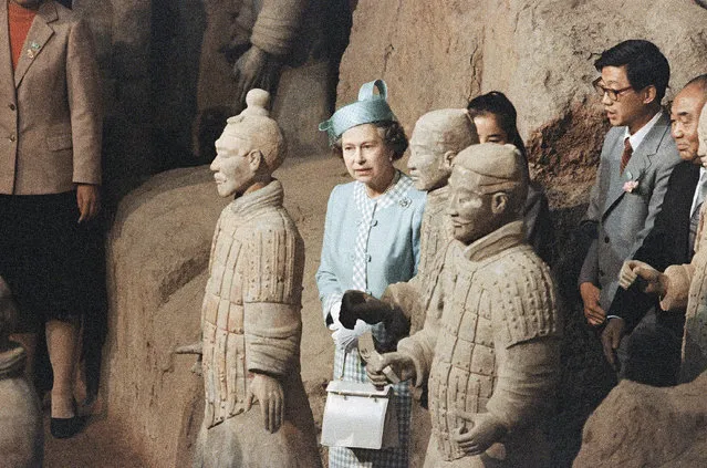 Queen Elizabeth II's hat resembles one of a 2000-year-old terracotta warrior she saw while visiting Xian, China on Thursday, October 16, 1986. Queen wears blue outfit. Warriors are brown-grey. (Photo by AP Photo/Bregg)