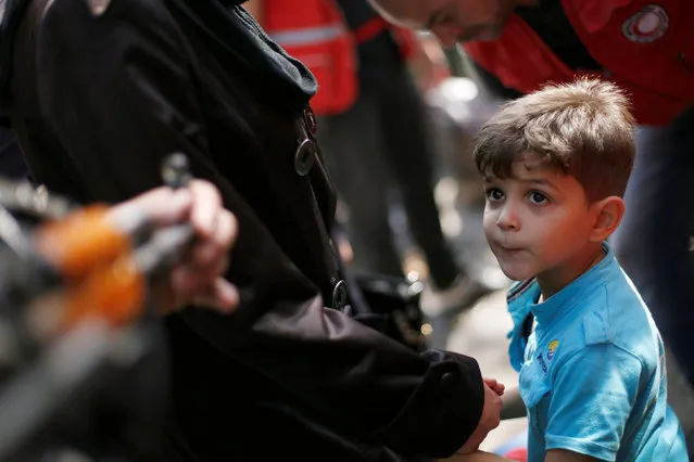 A boy, a relative of a rebel fighter, waits to board a bus to evacuate the besieged Waer district in the central Syrian city of Homs, after a local agreement reached between rebels and Syria's army, Syria September 22, 2016. (Photo by Omar Sanadiki/Reuters)