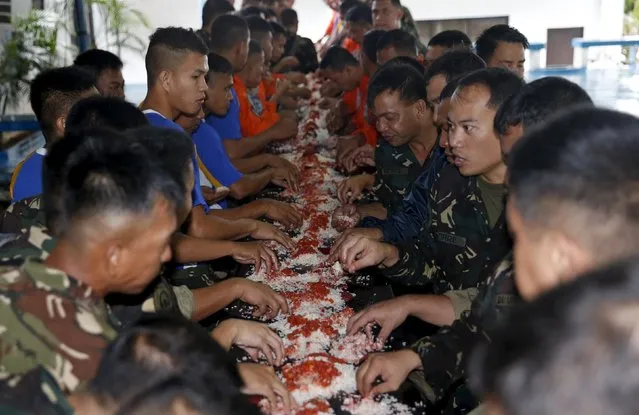Members of Mobile Disasters Rescue Unit (MDRU) of Philippine Air Force eat a "Boodle Fight" style meal as they wait for deployment to disaster areas affected by Typhoon Koppu in Pasay City, Metro Manila, October 18, 2015. (Photo by Erik De Castro/Reuters)
