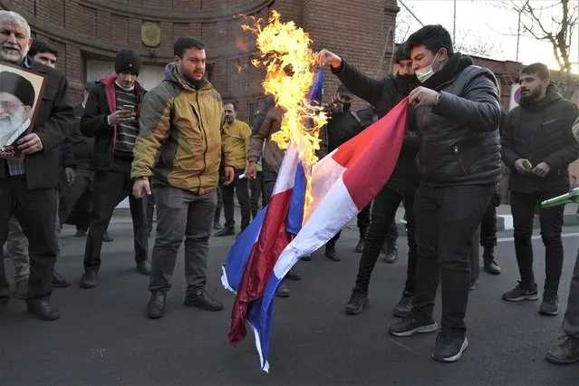 Iranian demonstrators set fire to French flags during their gathering to protest against the publication of offensive caricatures of the Iranian Supreme Leader Ayatollah Ali Khamenei in the French satirical magazine Charlie Hebdo, in front of the French Embassy in Tehran, Iran, Sunday, January 8, 2023. (Photo by Vahid Salemi/AP Photo)
