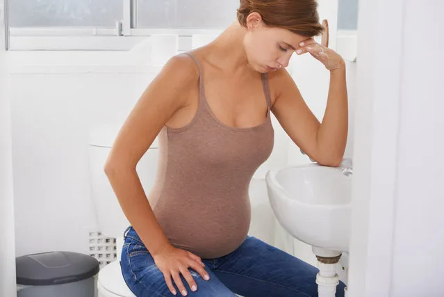 A pregnant woman struggling with morning sickness in the bathroom. (Photo by Yuri Arcurs/Getty Images)