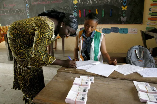 A resident signs to collect her voting card  during distribution of voting cards ahead of the country's presidential election that will be held on October 31, 2020 in Abidjan, Ivory Coast, 21 October 2020. (Photo by Legnan Koula/EPA/EFE/Rex Features/Shutterstock)