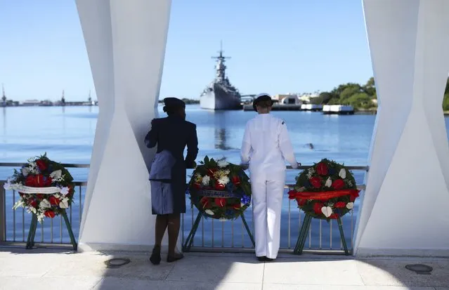 Senior Airman Ebony Jackson of the US Air Force (L) and Gunners Mate 3rd Class Lillian Collins of the US Navy look at the wreckage of the sunken USS Arizona from the deck of the USS Arizona Memorial, during ceremonies honoring the 73rd anniversary of the attack on Pearl Harbor at the World War II Valor in the Pacific National Monument in Honolulu, Hawaii December 7, 2014. (Photo by Hugh Gentry/Reuters)