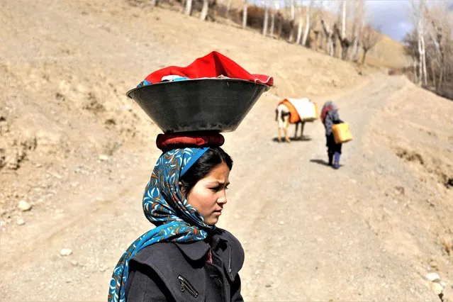 An Afghan girl carries washed clothes on her head in Bamiyan, Afghanistan on March 2, 2023. (Photo by Ali Khara/Reuters)