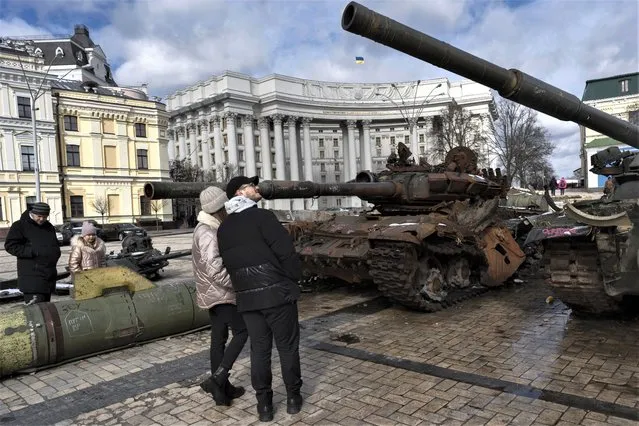 People watch destroyed Russian tanks and armoured vehicles on display near the St. Michael's Cathedral in downtown Kyiv, Ukraine, Sunday, March 12, 2023. (Photo by Andrew Kravchenko/AP Photo)