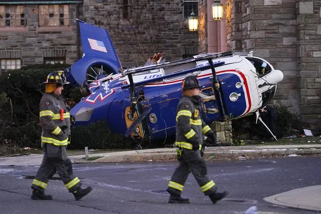 A medical helicopter rests next to the Drexel Hill United Methodist Church after it crashed in the Drexel Hill section of Upper Darby, Pa., on Tuesday, January 11, 2022. Authorities and a witness say a pilot crash landed a medical helicopter without casualties in a residential area of suburban Philadelphia, miraculously avoiding a web of power lines and buildings as the aircraft fluttered, hit the street and slid into bushes outside a church. (Photo by Matt Rourke/AP Photo)