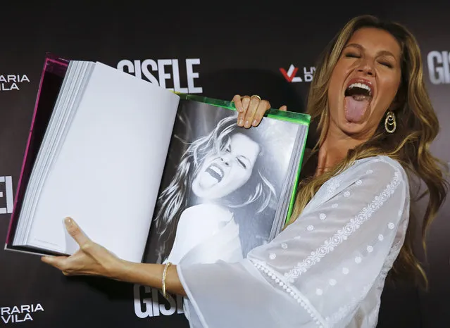 Brazilian model Gisele Bundchen imitates her own gesture as she shows a page of her book, titled Gisele Bundchen, about her 20-year modeling career, before signing autographs in Sao Paulo, Brazil, Friday, November 6, 2015. (Photo by Andre Penner/AP Photo)