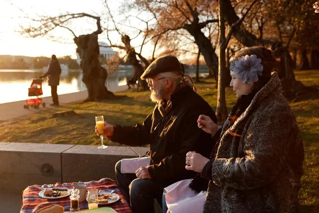 Elizabeth Willson and Garland Phillips greet the sunrise with a picnic breakfast amongst the cherry blossoms, which officials expect to reach their peak in the next few days, along the Tidal Basin in Washington, U.S. March 20, 2023. (Photo by Jonathan Ernst/Reuters)