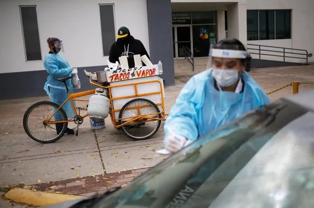 A health worker buys food from a street vendor, during a drive-thru vaccination campaign against influenza, as the coronavirus disease (COVID-19) outbreak continues, in Ciudad Juarez, Mexico on December 10, 2020. (Photo by Jose Luis Gonzalez/Reuters)