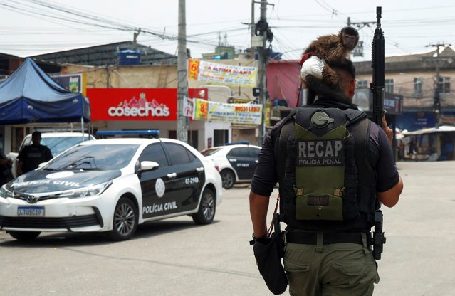 A member of the police walks with a monkey on his shoulder during a police operation against drug trafficking at the favela do Penha, in Rio de Janeiro, Brazil on October 28, 2025. (Photo by Aline Massuca/Reuters)