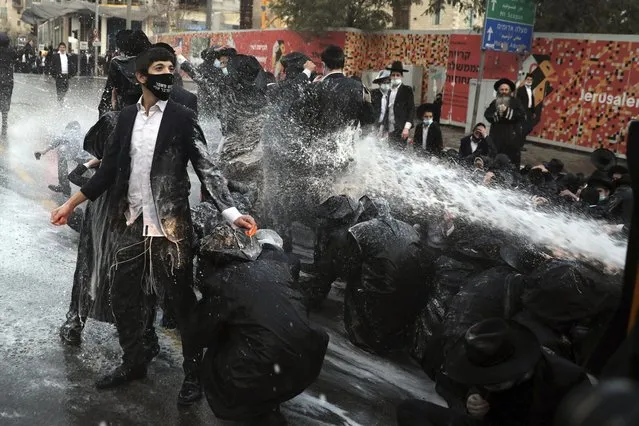 Israeli police shoot a water cannon towards ultra-Orthodox Jewish men blocking the road during a demonstration in Jerusalem, Tuesday, December 22, 2020. (Photo by Mahmoud Illean/AP Photo)