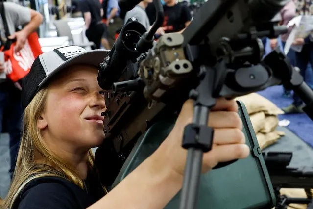 Kierstyn Hendrix, 14, from Illinois holds a machine gun at the National Rifle Association (NRA) annual convention in Indianapolis, Indiana, U.S., April 14, 2023. (Photo by Evelyn Hockstein/Reuters)