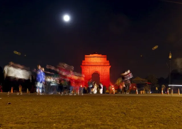 Visitors cross a road near the illuminated India Gate war memorial in New Delhi, India, November 25, 2015. The India Gate was illuminated in Orange on Wednesday to commemorate the International Day for the Elimination of Violence Against Women, according to a media release issued by the organisers. (Photo by Anindito Mukherjee/Reuters)