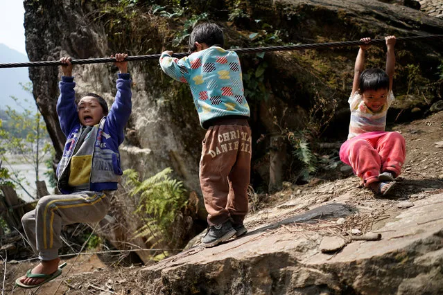Village children play with a zipline cable in Nujiang Lisu Autonomous Prefecture in Yunnan province, China, March 24, 2018. People estimate about 20 to 30 hamlets in the region still rely on the ziplines as their primary means across the river, although the lines are not always reliable, since they become slippery when it rains and too dangerous to use. (Photo by Aly Song/Reuters)
