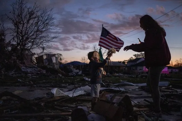 Four-year-old Jackson Zoller excitedly hands family friend Elena Ozuna, 17, a doll while hunting for what he said was “treasure” in the remains of his neighbor's home which was levelled by a tornado in Arabi, St. Bernard Parish, in the outskirts of New Orleans, Louisiana, U.S. March 24, 2022. The Zoller family's residence, situated directly across the street, went unharmed. (Photo by Adrees Latif/Reuters)