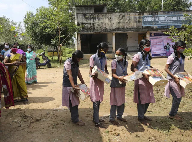 Schoolgirls carry boxes of packaged food and sweets sent by a non-government organization to be distributed among school children and villagers ahead of the inauguration of U.S. Vice President-elect Kamala Harris, in Thulasendrapuram, the hometown of Harris' maternal grandfather, south of Chennai, Tamil Nadu state, India, Tuesday, January 19, 2021. (Photo by Aijaz Rahi/AP Photo)
