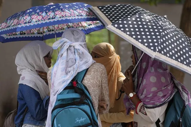 Allahabad university students hold umbrellas as they chat on a hot afternoon in Prayagraj, Uttar Pradesh, India, Monday, May 22, 2023. As temperatures crossed 45 degrees Celsius (113 degrees Fahrenheit) in this northern state, some parts suffered blackouts lasting more than 12 hours. (Photo by Rajesh Kumar Singh/AP Photo)