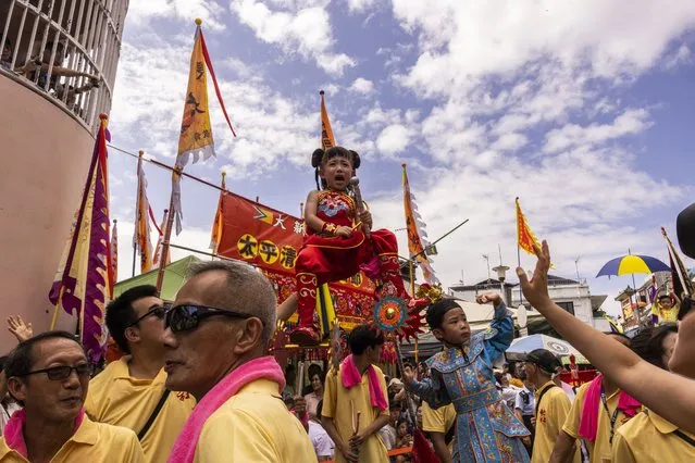A child reacts as she is hoisted up during the Piu Sik Parade at the Bun Festival in Cheung Chau Island in Hong Kong, Friday, May 26, 2023. (Photo by Louise Delmotte/AP Photo)
