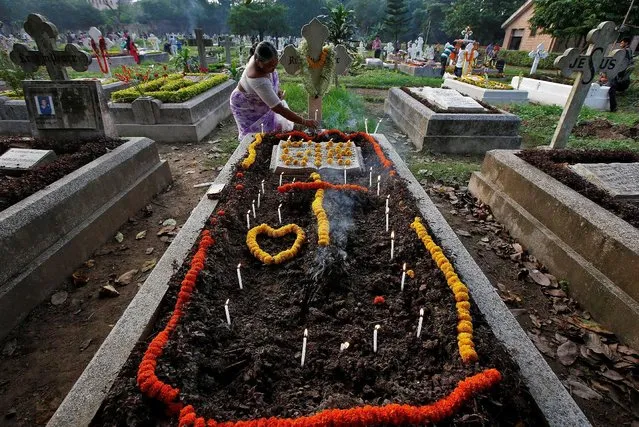 A woman lights a candle on the grave of her relative before praying at a cemetery during the observance of All Souls Day in Kolkata, India November 2, 2016. (Photo by Rupak De Chowdhuri/Reuters)