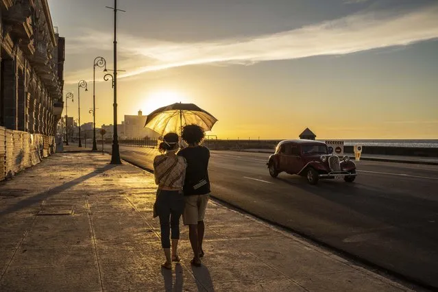 A couple wearing masks as a precaution against the spread of the new coronavirus walk on the Malecon seawall at sunset in Havana, Cuba, Monday, August 31, 2020. Cuban authorities will introduce new measures starting tomorrow Tuesday aimed at containing the spread of the coronavirus in Havana among others a curfew from 7 pm until 5 am and no one without special permission will be able to enter or leave the province. The new measures will last at least 15 days. (Photo by Ramon Espinosa/AP Photo)