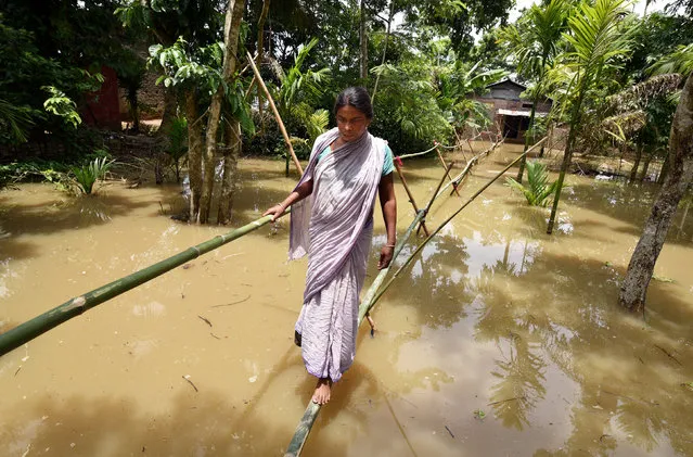 A villager uses a makeshift bamboo bridge to cross a flooded area in the Nagaon district, in the northeastern state of Assam, India, June 18, 2018. (Photo by Anuwar Hazarika/Reuters)
